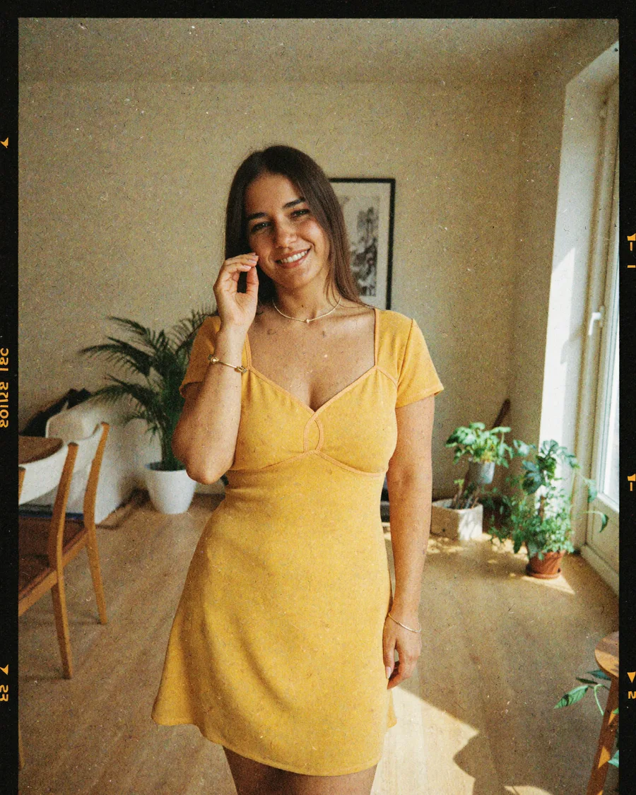 Moni in a sunlit room in a yellow dress