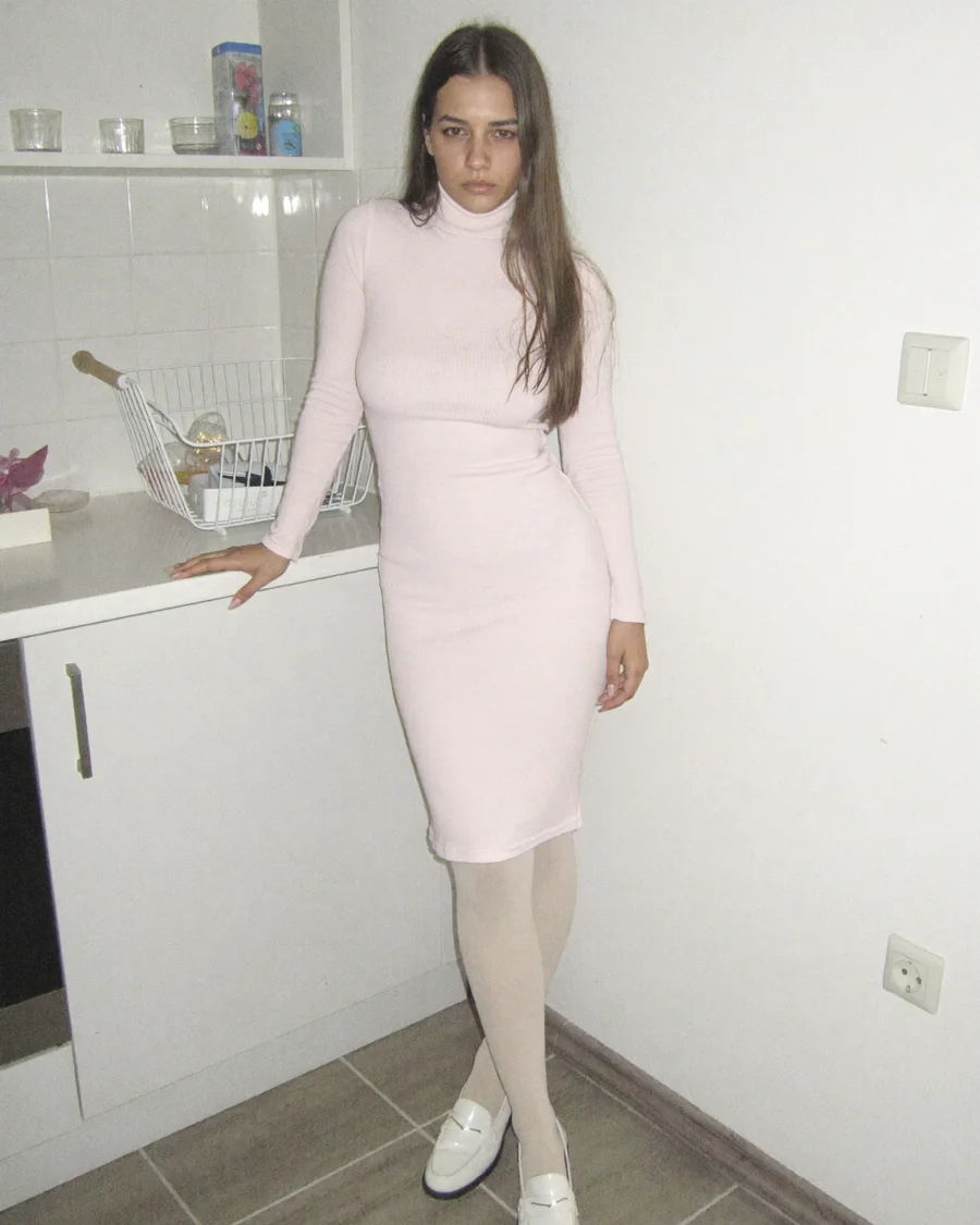 Moni in a light interior in a fitted dress