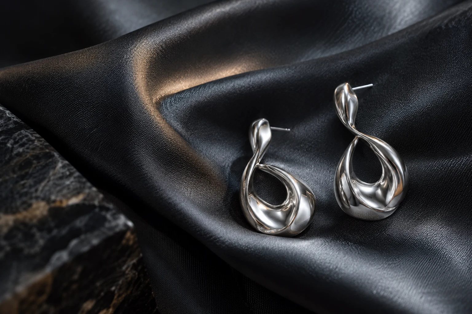 Sculptural silver earrings on satin — original AI concept